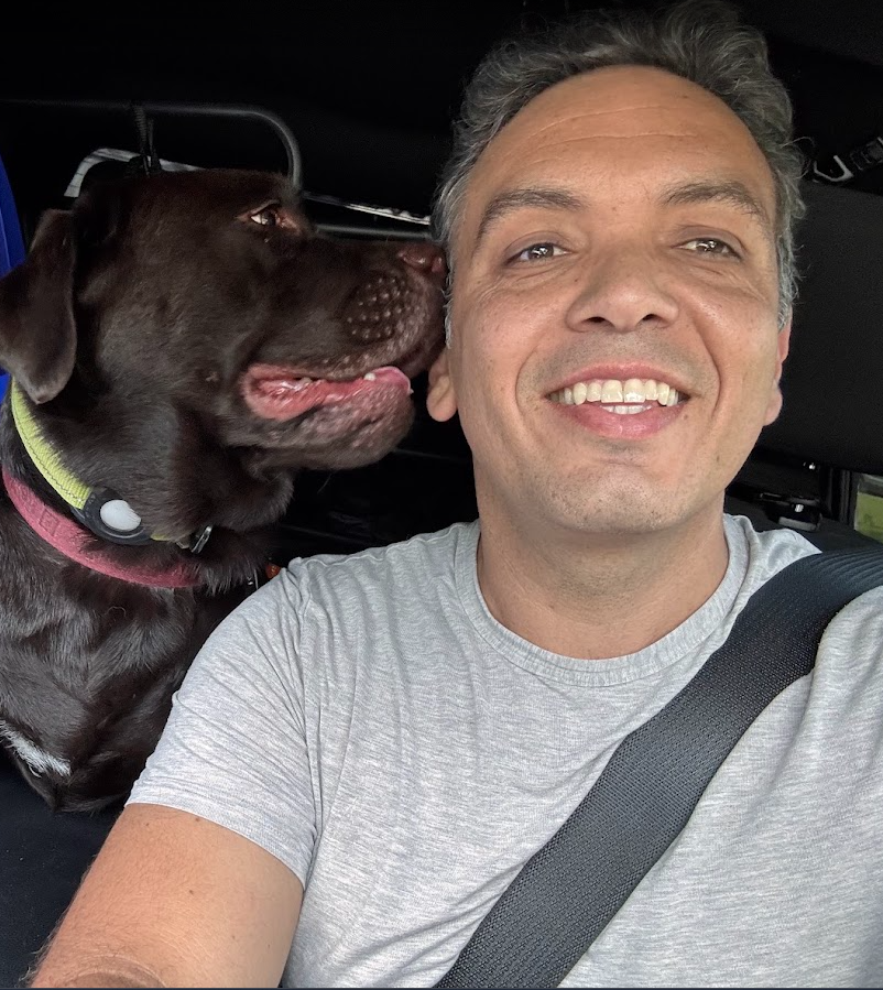 Kaio smiling with a chocolate Labrador during a car ride